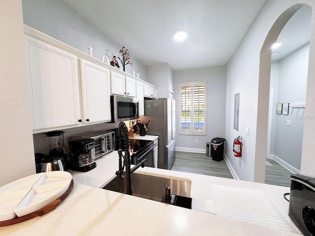 kitchen featuring white cabinets, appliances with stainless steel finishes, and hardwood / wood-style flooring