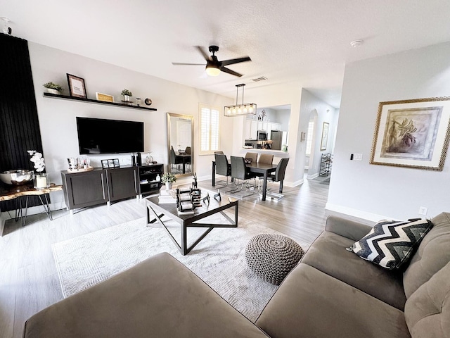 living room with a textured ceiling, light hardwood / wood-style floors, and ceiling fan