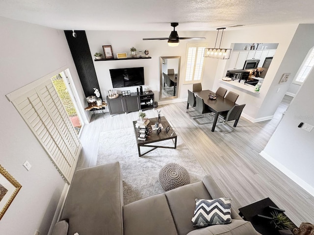 living room with ceiling fan, light hardwood / wood-style flooring, and a textured ceiling