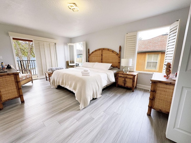 bedroom featuring a textured ceiling, access to outside, and light hardwood / wood-style flooring