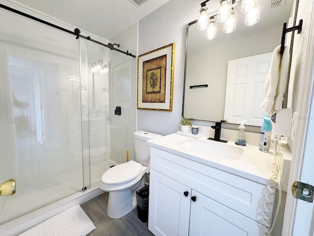 bathroom featuring wood-type flooring, vanity, toilet, and a shower with shower door