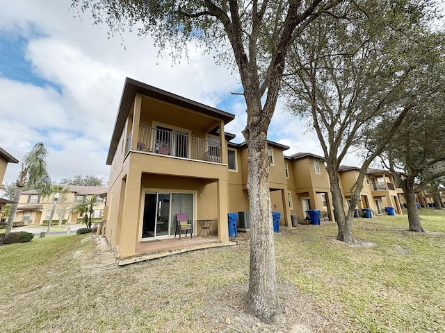 back of property featuring a balcony, central AC unit, and a lawn