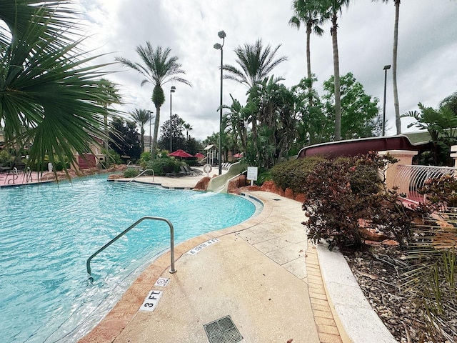 view of swimming pool with a patio area and a water slide