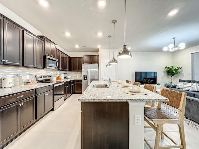 4190 Lana Ave, Davenport, FL 33897 - kitchen with appliances with stainless steel finishes, open floor plan, a breakfast bar area, decorative backsplash, and dark brown cabinets