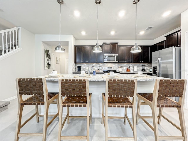 kitchen with a breakfast bar, appliances with stainless steel finishes, backsplash, and pendant lighting