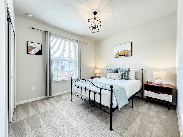 carpeted bedroom with a closet, a textured ceiling, and a notable chandelier