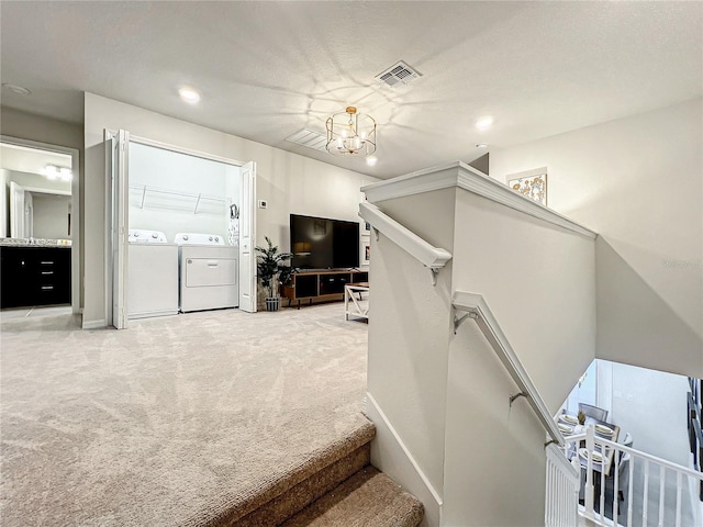 stairway featuring washing machine and dryer, carpet floors, a textured ceiling, and a notable chandelier