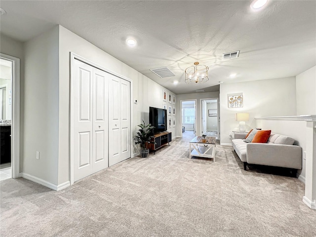 carpeted living room featuring a chandelier and a textured ceiling