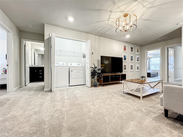 carpeted living room with a chandelier, a textured ceiling, and washing machine and clothes dryer