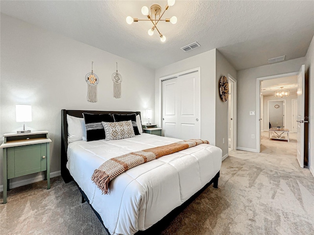 carpeted bedroom featuring an inviting chandelier, a textured ceiling, and a closet