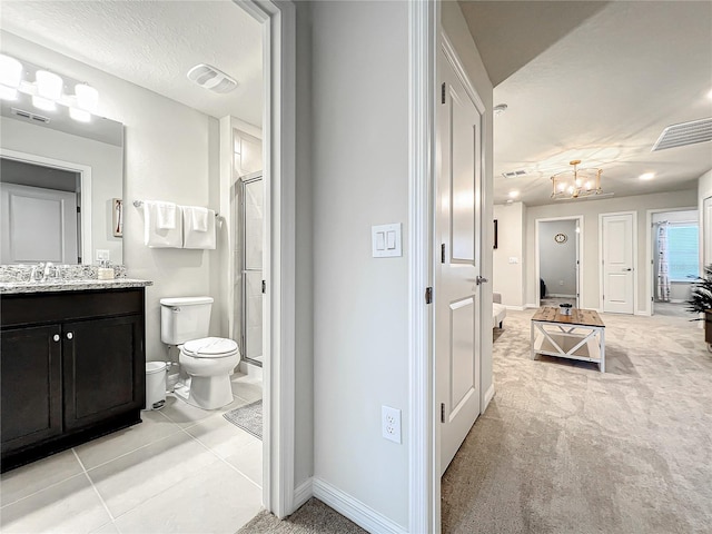 bathroom featuring a notable chandelier, tile patterned floors, toilet, vanity, and a shower with shower door