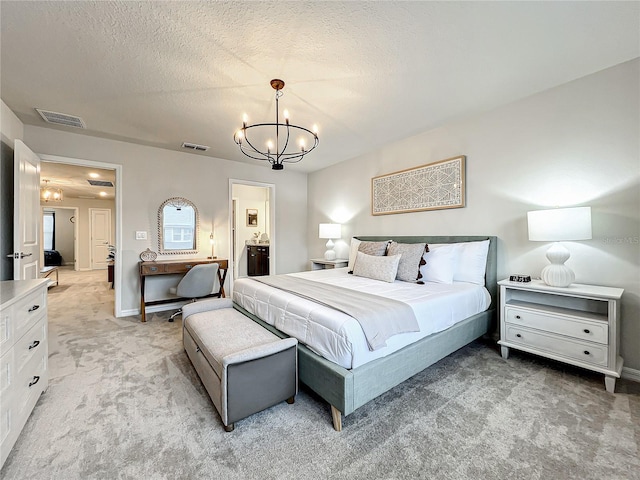 carpeted bedroom featuring ensuite bathroom, a textured ceiling, and an inviting chandelier