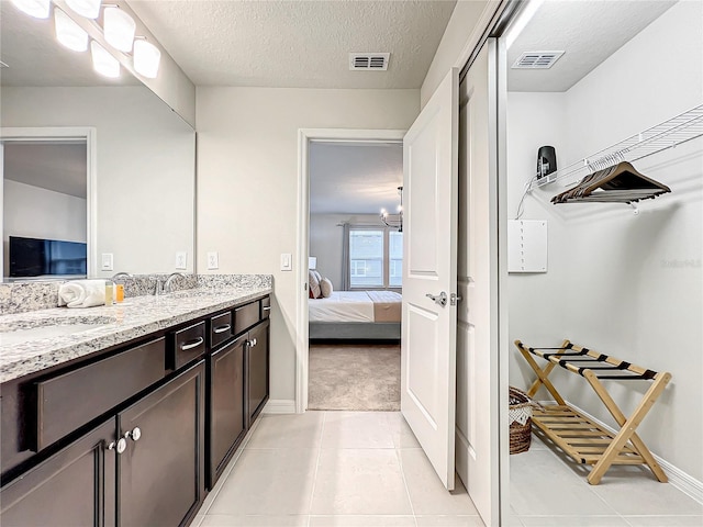 bathroom with tile patterned floors, vanity, and a textured ceiling