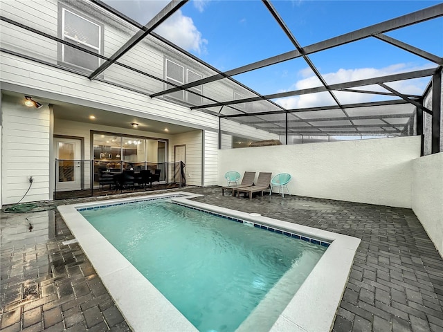 view of swimming pool featuring a patio and a lanai