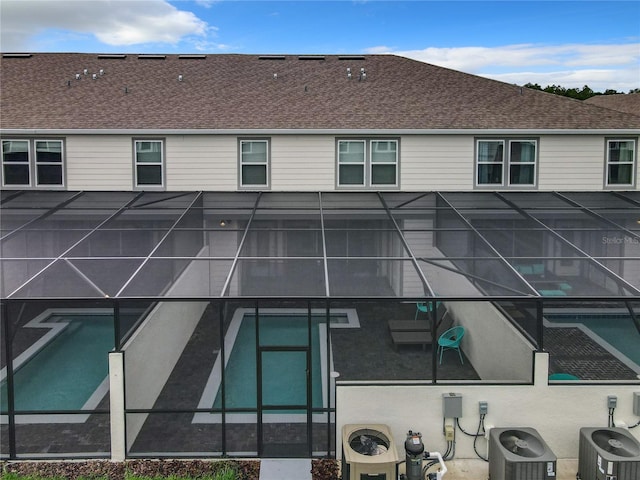 back of property with glass enclosure and central air condition unit