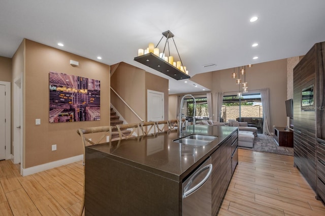 kitchen featuring a kitchen island with sink, dishwasher, light hardwood / wood-style flooring, and sink