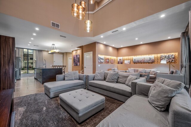 living room with wood-type flooring, sink, a high ceiling, and an inviting chandelier