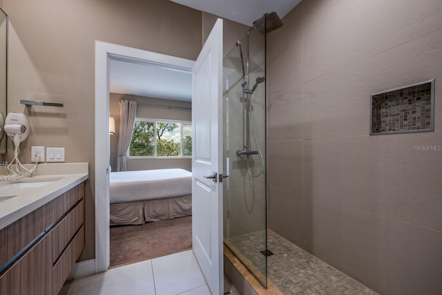 bathroom with tile patterned flooring, vanity, and tiled shower