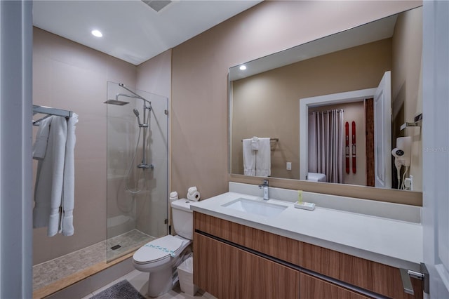 bathroom with tile patterned flooring, vanity, a shower with shower door, and toilet