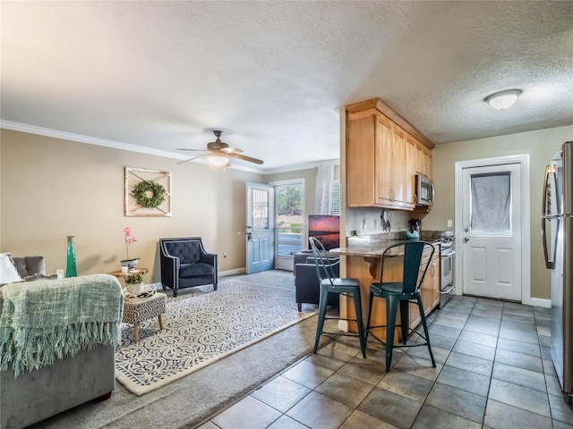 kitchen featuring a breakfast bar, crown molding, light brown cabinetry, appliances with stainless steel finishes, and kitchen peninsula