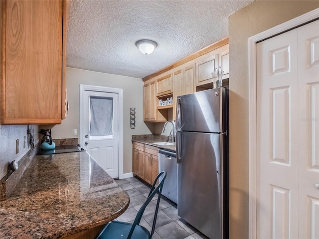 kitchen featuring appliances with stainless steel finishes, light brown cabinetry, a textured ceiling, sink, and light tile patterned floors