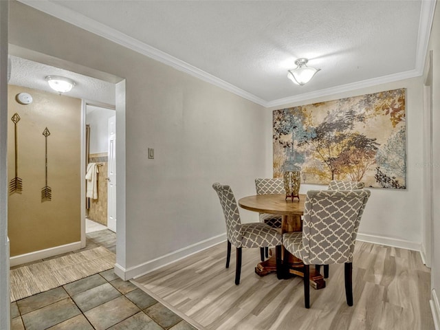 dining space with baseboards, crown molding, a textured ceiling, and tile patterned floors