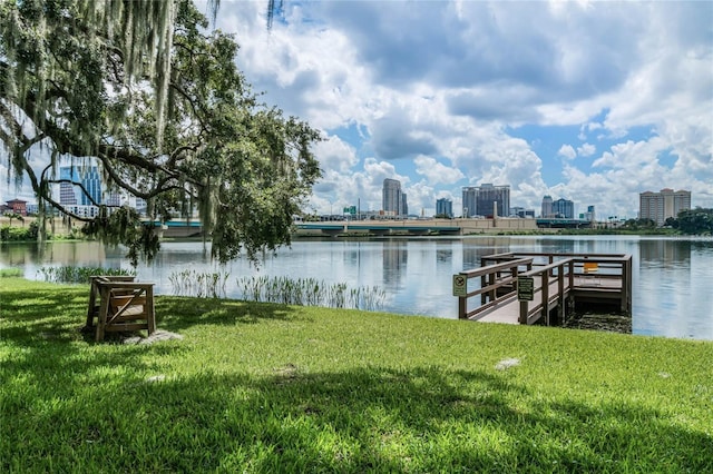 dock area with a lawn, a water view, and a view of city