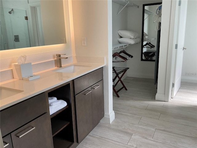 bathroom with a shower with door, vanity, and wood-type flooring