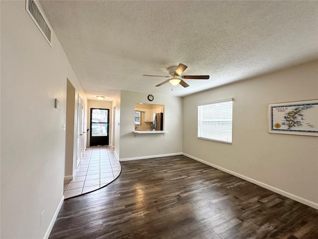 unfurnished living room with dark hardwood / wood-style floors, ceiling fan, and a textured ceiling