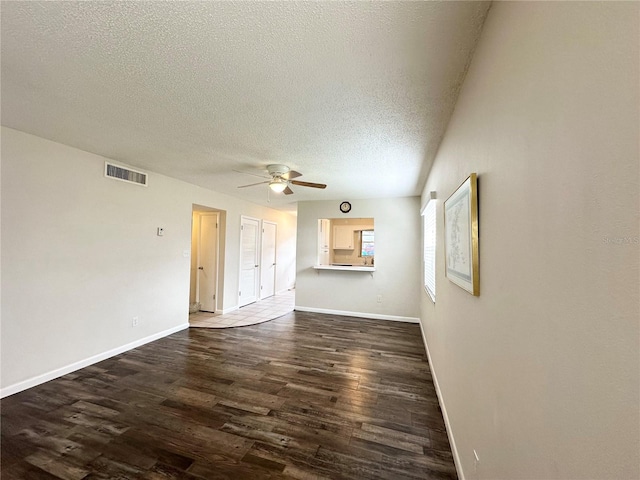 unfurnished living room featuring a textured ceiling, ceiling fan, and dark wood-type flooring