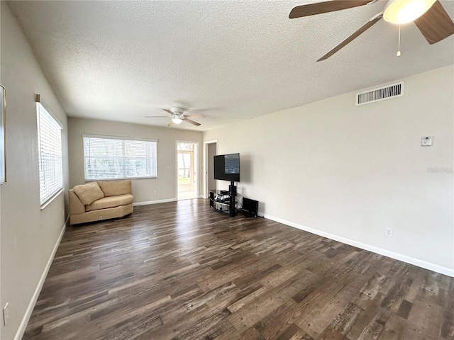 unfurnished living room featuring dark hardwood / wood-style floors, ceiling fan, and a textured ceiling