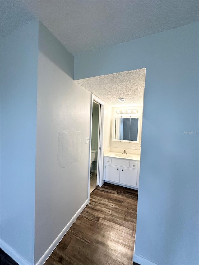 hall featuring sink, dark hardwood / wood-style flooring, and a textured ceiling