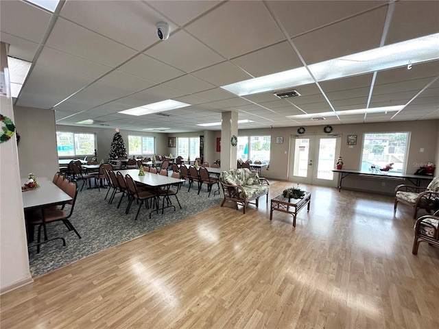 dining area with french doors, wood-type flooring, a paneled ceiling, and a wealth of natural light