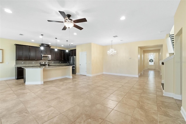 kitchen with ceiling fan with notable chandelier, hanging light fixtures, decorative backsplash, an island with sink, and appliances with stainless steel finishes