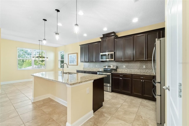 kitchen with backsplash, sink, an island with sink, decorative light fixtures, and stainless steel appliances