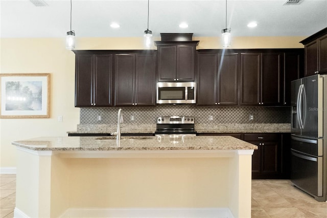 kitchen with decorative light fixtures, light stone countertops, stainless steel appliances, and a kitchen island with sink