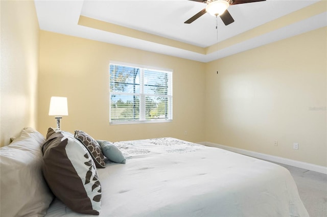 bedroom with a raised ceiling, ceiling fan, and carpet floors