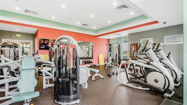 gym featuring a raised ceiling and ornamental molding