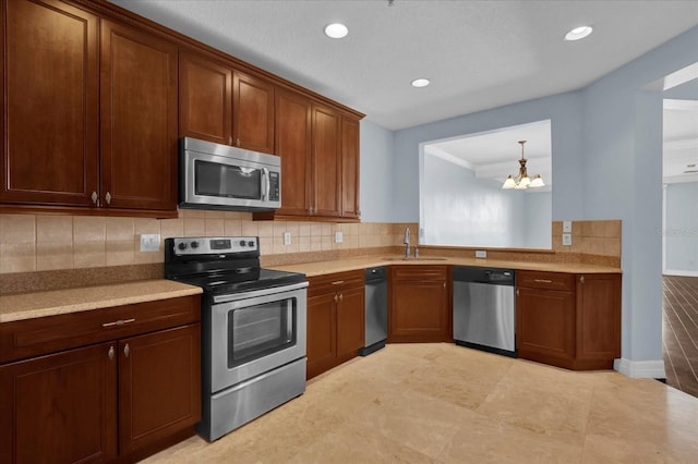 kitchen featuring appliances with stainless steel finishes, backsplash, sink, a chandelier, and hanging light fixtures