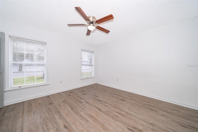 spare room featuring a wealth of natural light, light hardwood / wood-style flooring, ceiling fan, and a textured ceiling