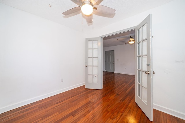 empty room with a textured ceiling, ceiling fan, dark wood-type flooring, and french doors