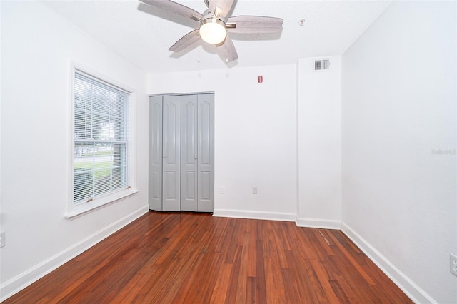 unfurnished bedroom with ceiling fan, a closet, and dark hardwood / wood-style floors