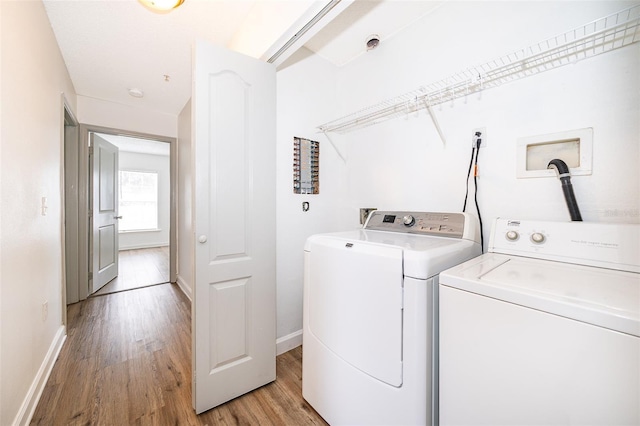 clothes washing area with washer and dryer and light hardwood / wood-style flooring