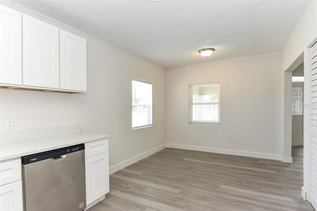 kitchen with light countertops, light wood-style flooring, white cabinets, dishwasher, and baseboards