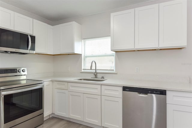 kitchen featuring light countertops, appliances with stainless steel finishes, white cabinetry, a sink, and light wood-type flooring