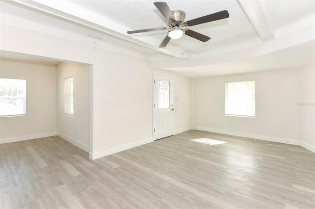 spare room with light wood-style floors, plenty of natural light, beamed ceiling, and baseboards