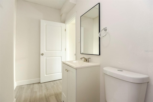 bathroom featuring baseboards, vanity, toilet, and wood finished floors