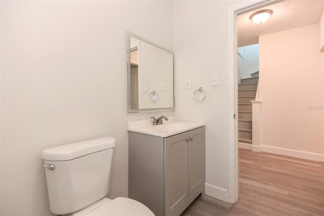 bathroom featuring baseboards, vanity, toilet, and wood finished floors