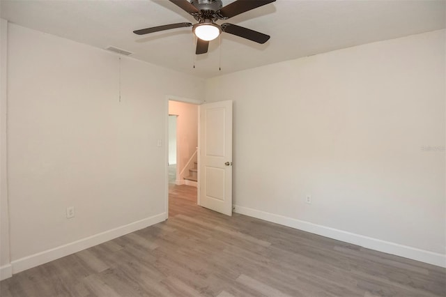 spare room featuring attic access, wood finished floors, visible vents, and baseboards