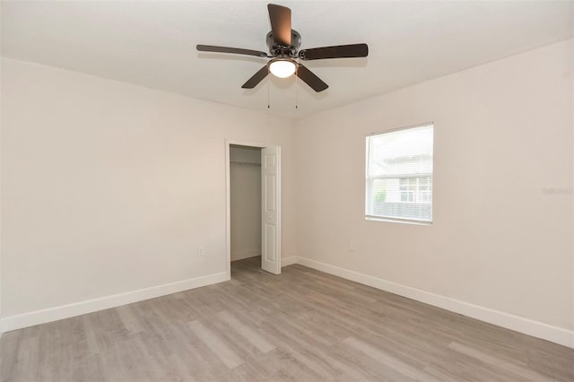 unfurnished bedroom with light wood-style flooring, baseboards, ceiling fan, and a closet